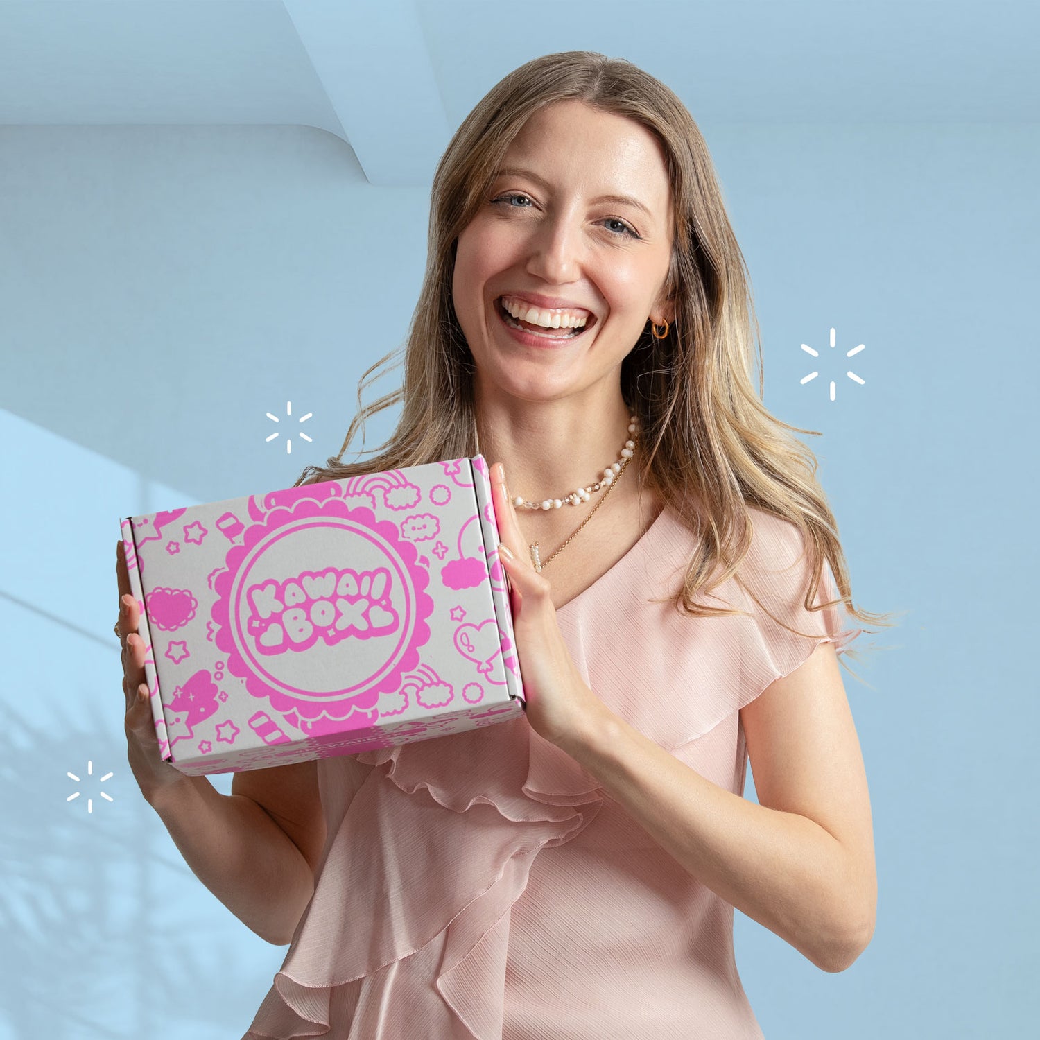Woman holding a pink Kawaii Box subscription box against a light blue background