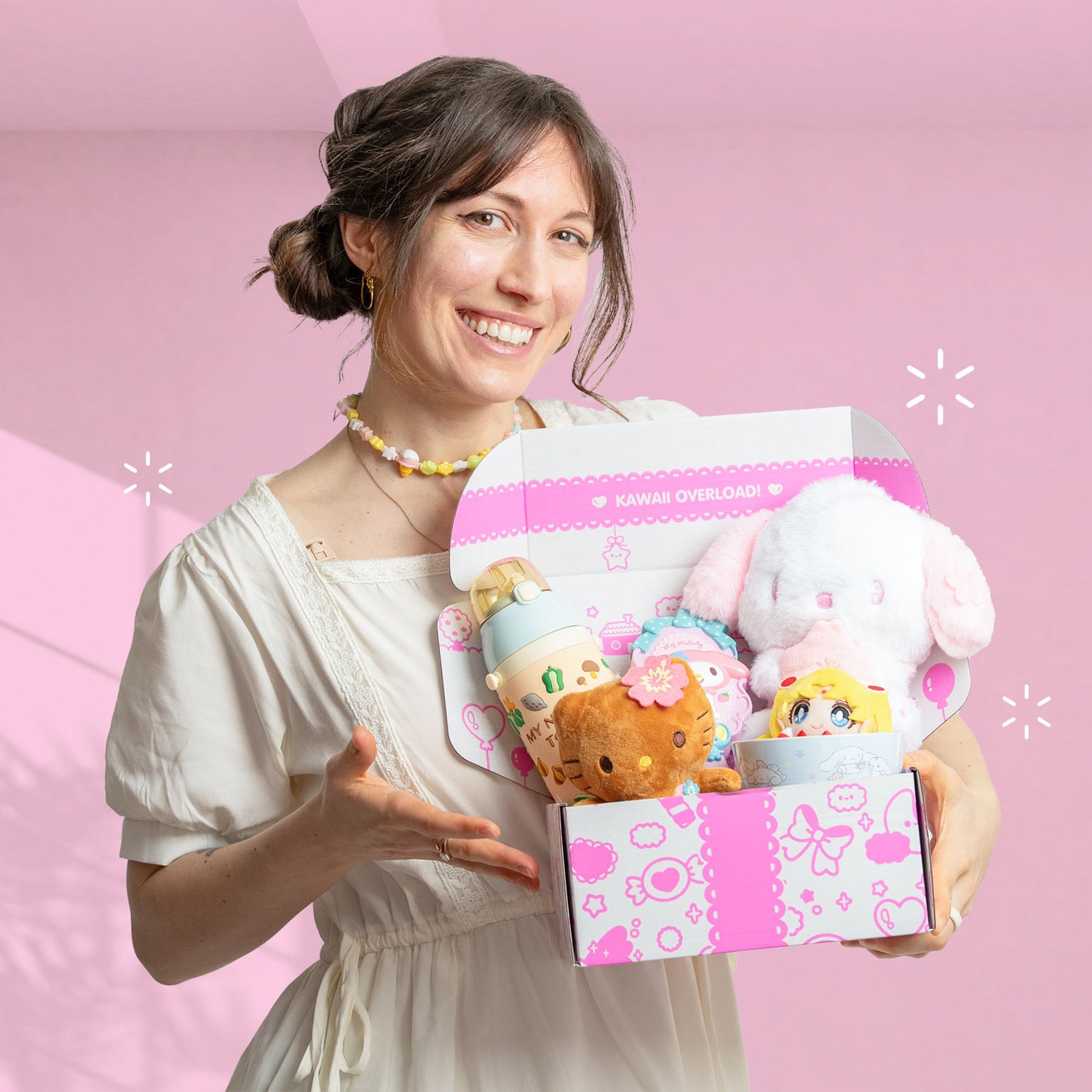 Woman holding a box of kawaii plush toys against a pink background
